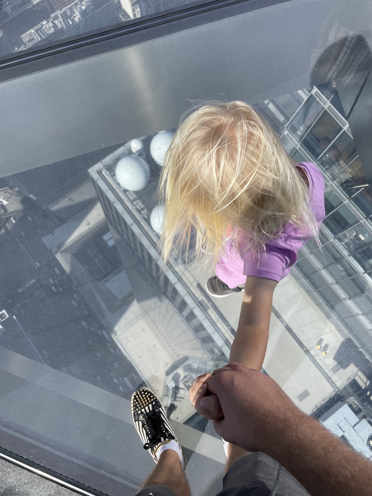 A view of a city street below from a window in the floor of the observation deck